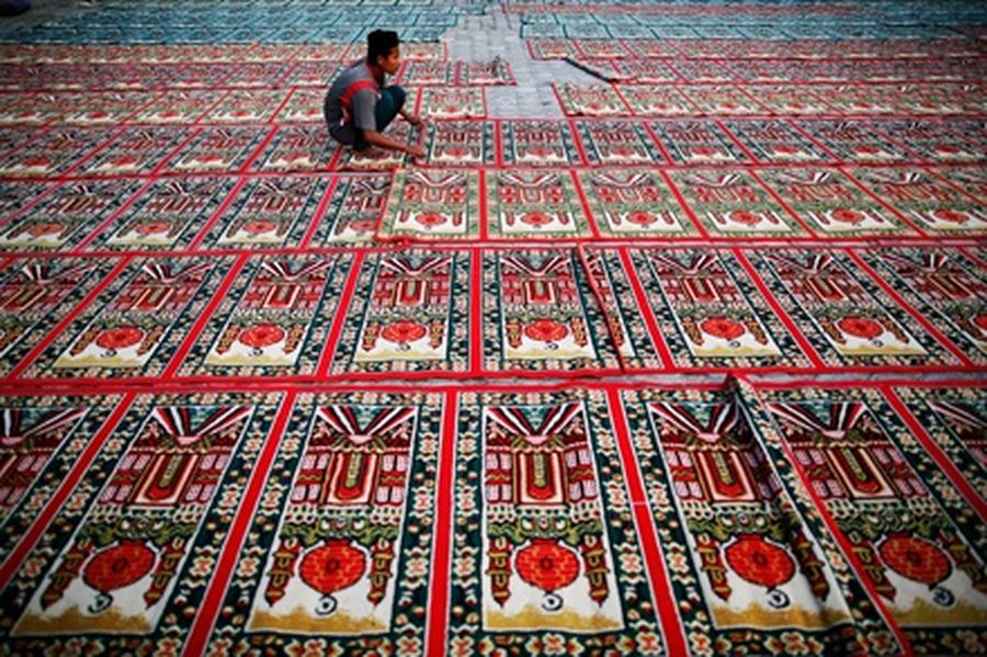 A man prepares carpets for Muslim worshippers outside a mosque in Banda Aceh.