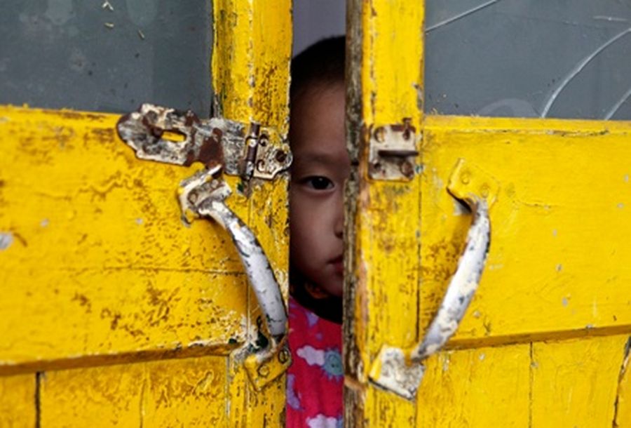 A three-year-old boy looks out from a door of a classroom in Tenglong kindergarten.