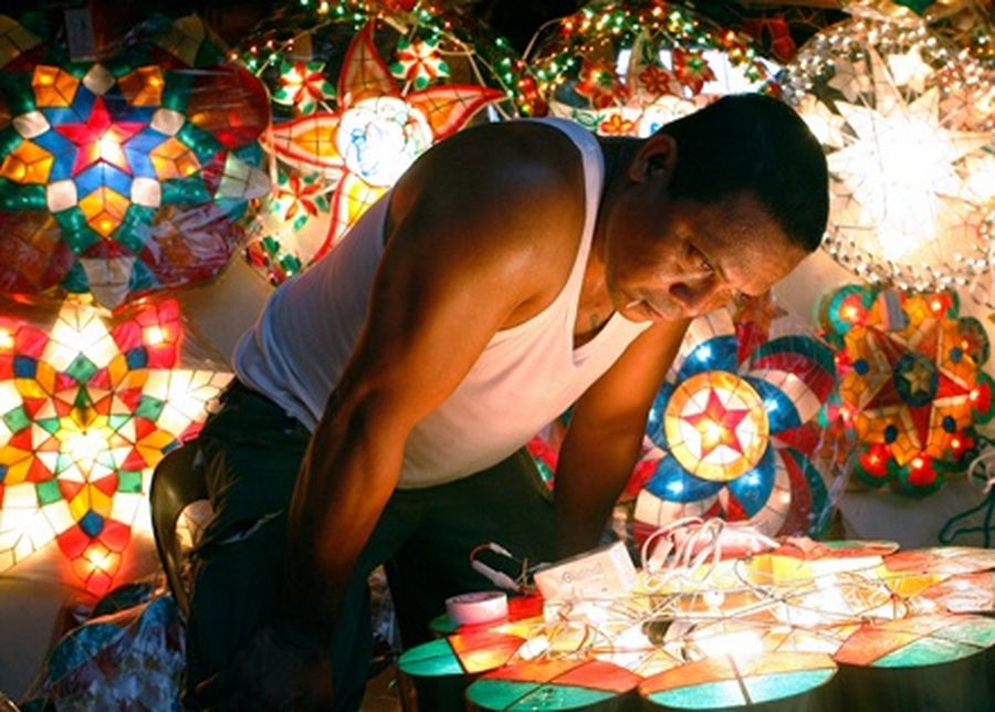 A worker inspects light bulbs installed on a Christmas lantern on sale along a street in Manila. 