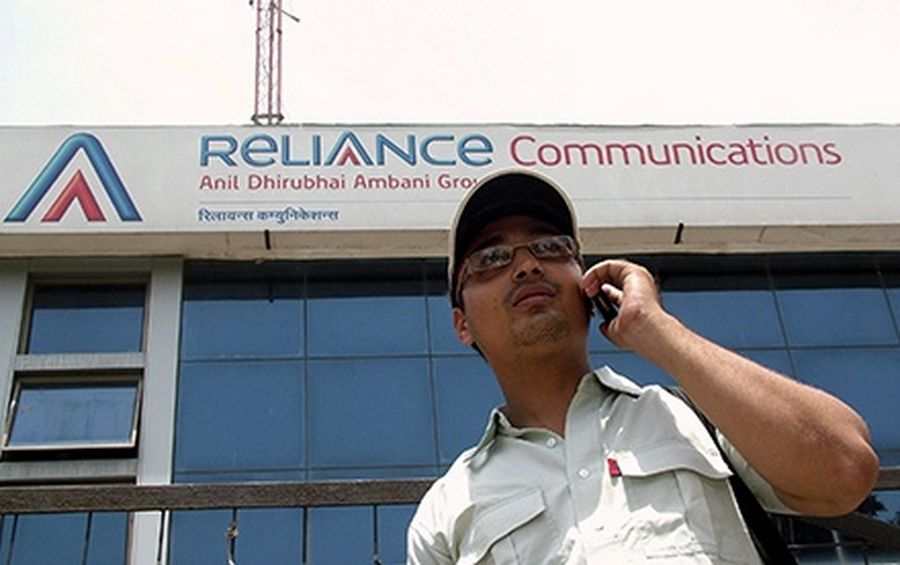 A man makes a call in front of an advertisement for India’s Reliance Communications in the northern Indian city of Mathura.