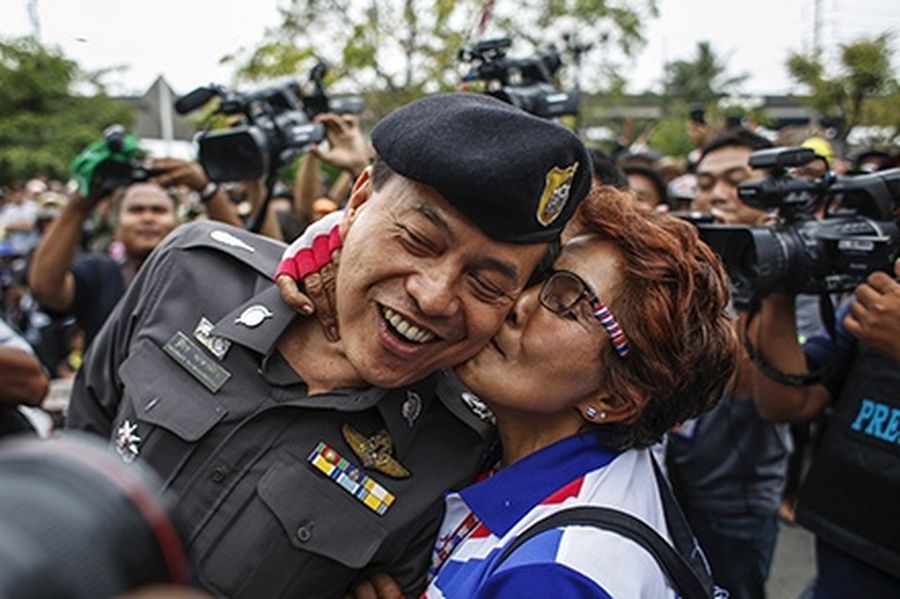 An anti-government protester kisses a police officer during a rally inside a compound of the Thai Royal Police Club in Bangkok.