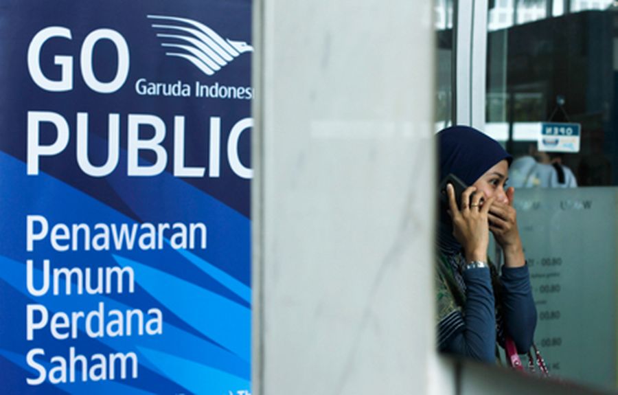 A woman uses her cellular phone near a banner of PT Garuda Indonesia in Jakarta