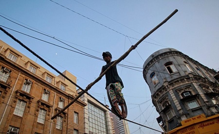 Raji, a 9-year-old tightrope walker, walks on a rope, while holding a balancing pole during a performance in Mumbai’s financial district.