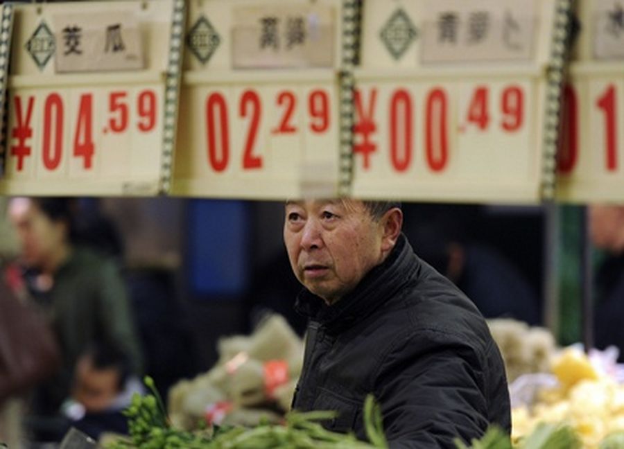 A customer looks at price tags at the vegetable section of a supermarket in Hefei
