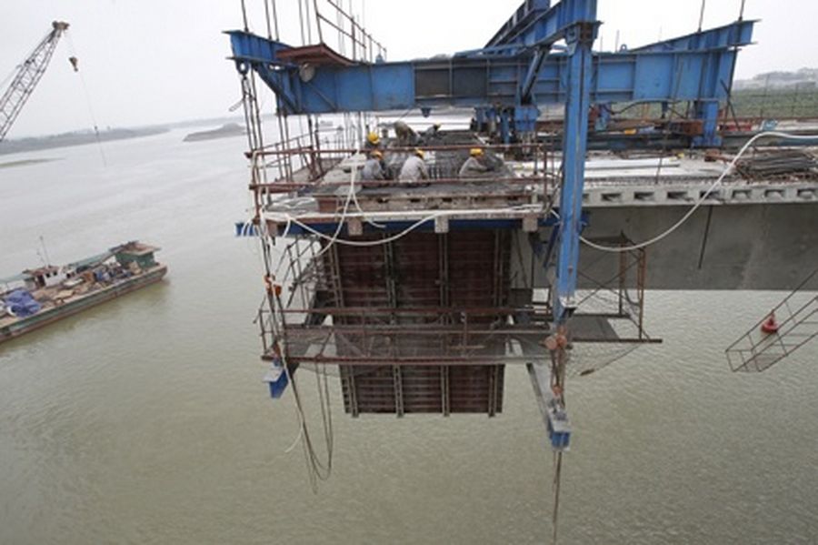 Labourers work on a bridge construction site, across the Duong river outside Hanoi. 