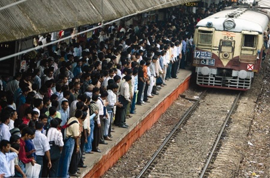 Commuters wait as a train approaches a railway station in Mumbai. 