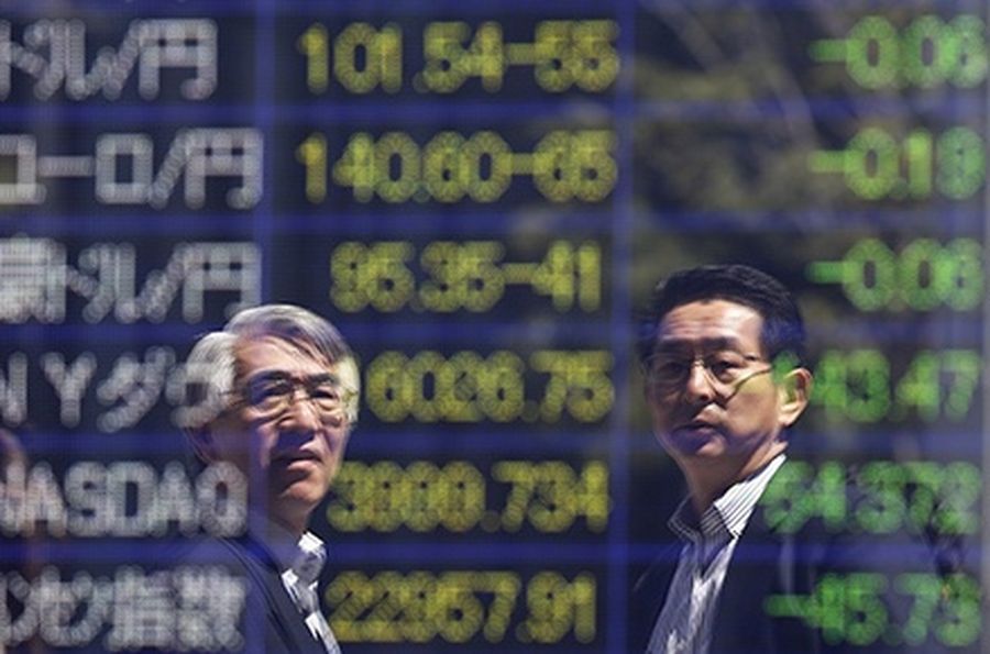 Tokyo businessmen are reflected in an electronic board showing exchange rates between (from top row to third row) the Japanese yen against the U.S. dollar, the euro, Australian dollar and (fourth row to bottom row) indices of Dow Jones, the NASDAQ and Han