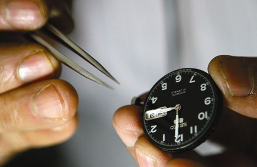 A man holds tweezers while repairing a watch at his workshop in Srinagar. 