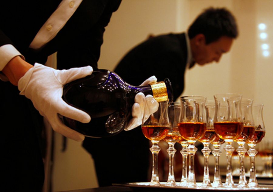 A waiter is reflected in a mirror as he pours luxury Scotch whisky Royal Salute into glasses in Beij