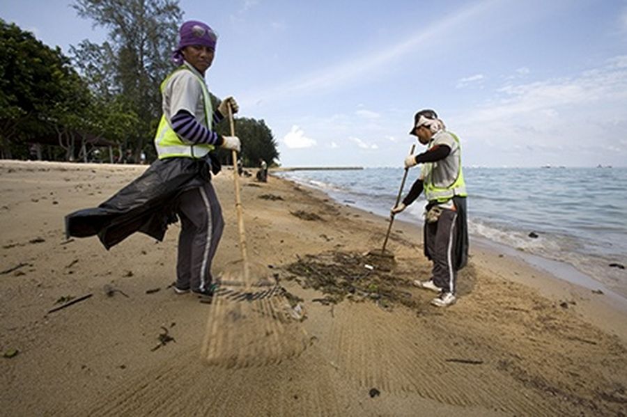 Workers from Ramky Cleantech Services clean up oil and debris from the beach at East Coast Park just east of the playground at Big Splash Water Park in Singapore.