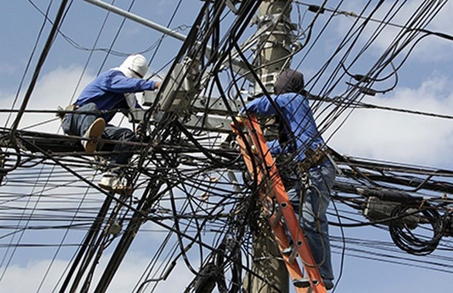 Workers try to locate illegal cable television connections from overhead wires inside a subdivision at Paranaque, Metro Manila. 
