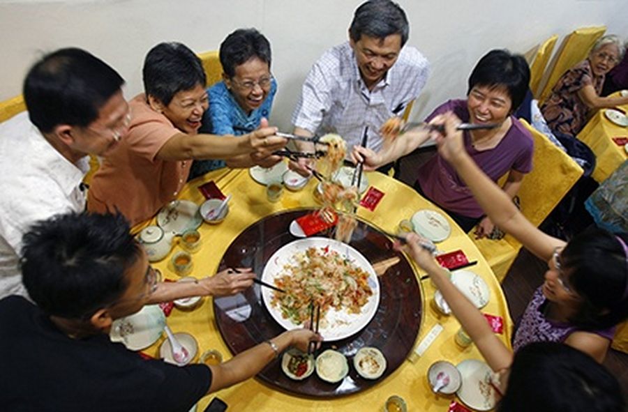 A Chinese family enjoys ‘lao yu sheng’ during a reunion dinner in Singapore.