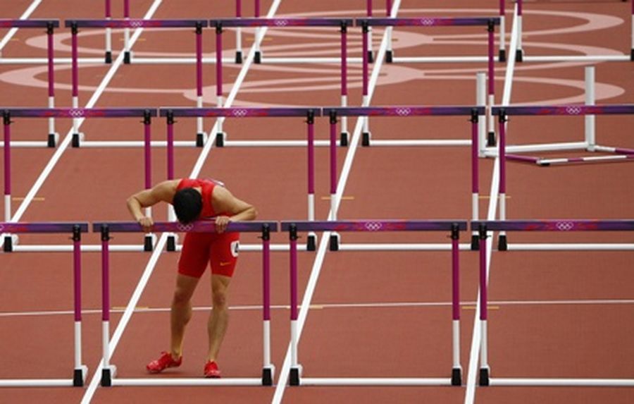China's Liu Xiang grabs the last hurdle in his lane after crashing and failing to finish his men's 110m hurdles Round 1 heat of the 2012 Olympic Games at the Olympic Stadium in London. 