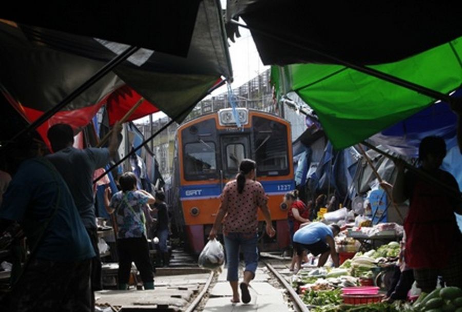 Thai market vendors pull back awnings and their produce off a railway track to allow a cross-country train to dissect through the middle of the town of Maeklong. 