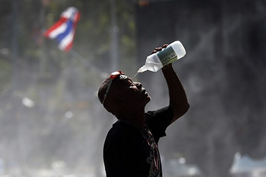 An anti-government protester recovers from teargas during clashes with police at the barricade in front of the Government House in Bangkok.