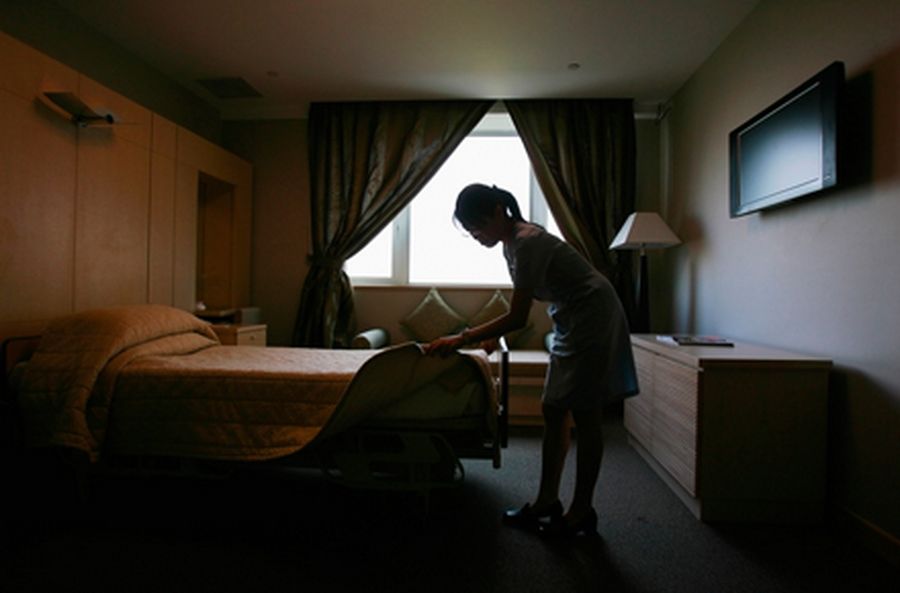 A nurse makes the bed inside a deluxe room at a hospital in Singapore.