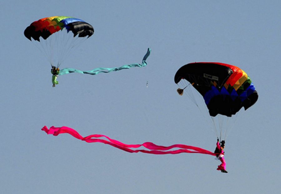 Soldiers wearing traditional costumes make parachute jump performances during a rehearsal nea