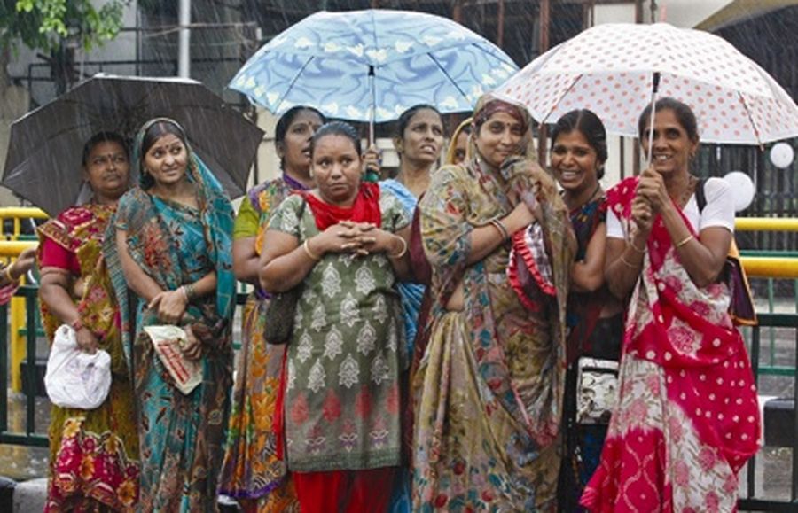 Women hold umbrellas to protect themselves from a heavy rain shower as they stand at a bus stop in the western Indian city of Ahmedabad. 