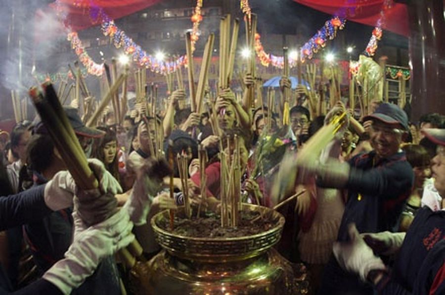 People rush to place joss sticks at the Guan Yin temple in Singapore.