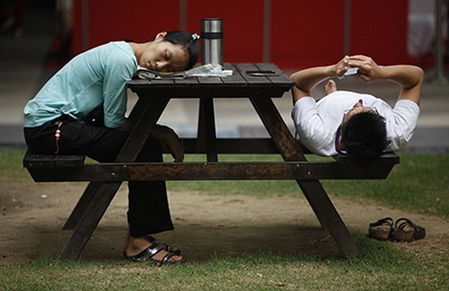 A woman sleeps at a bench at the end of a working day at the central business district in Singapore.