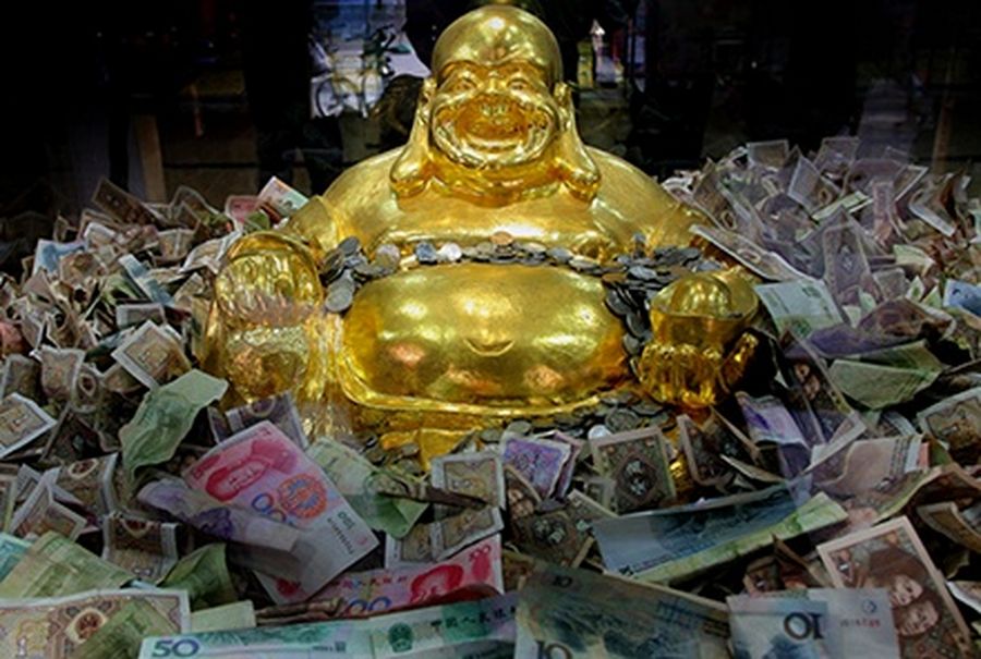 Chinese yuan bank notes are seen around a golden Buddha statue at a shopping mall in Nanjing, capital of east China’s Jiangsu province.