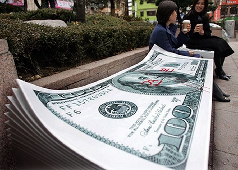 South Korean women sit on a bench in the shape of the 100 dollar U.S. bank note in front of Korea Exchange Bank in Seoul.